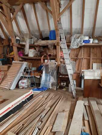 Dachboden mit Holzverkleidung, Bauholz, Werkzeugen und Leiter für Renovierungsarbeiten.