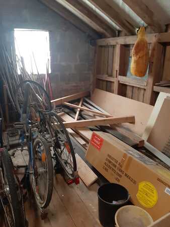 Dachboden mit alten Fahrrädern, Holzbrettern, Karton und hängendem Schinken.