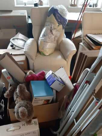 Ein Umzugschaos mit Kartons, Möbeln, Spielzeug und Haushaltsgegenständen im Wohnzimmer.