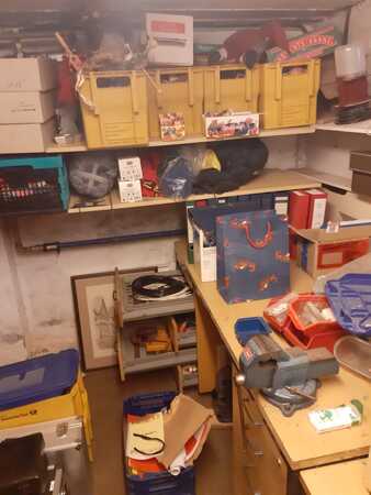 Kellerraum mit Regalen, Werkzeug, Kisten, Aktenordnern und verschiedenen Utensilien.